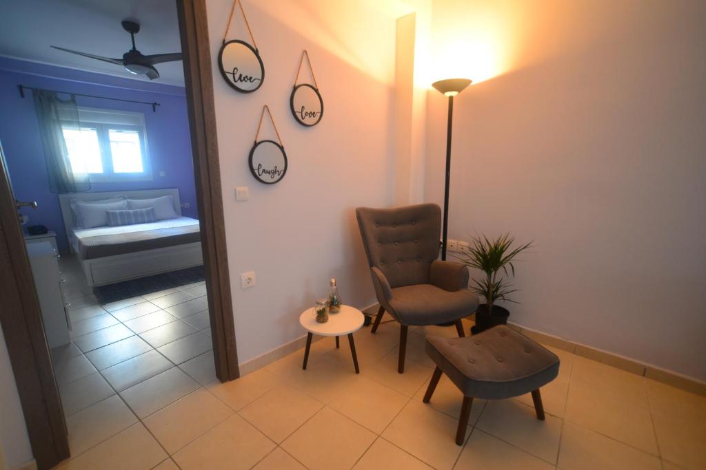 a room with a chair and a table and clocks on the wall at Karma - 2 bedroom apartment in Zakynthos Town