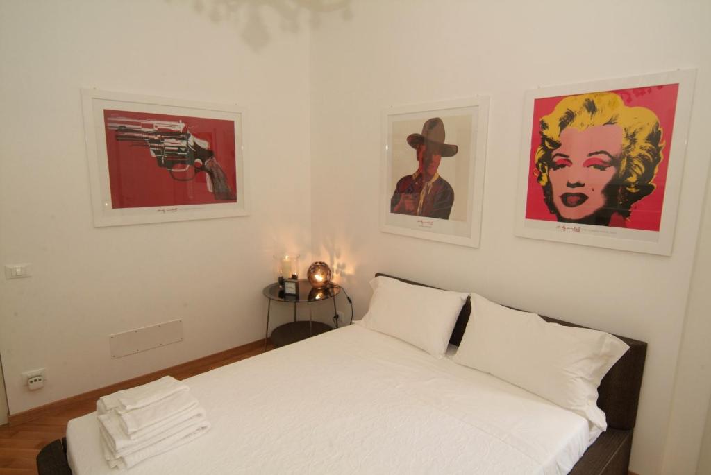 a bedroom with a white bed with three pictures on the wall at Vatican Sunset Guest House in Rome