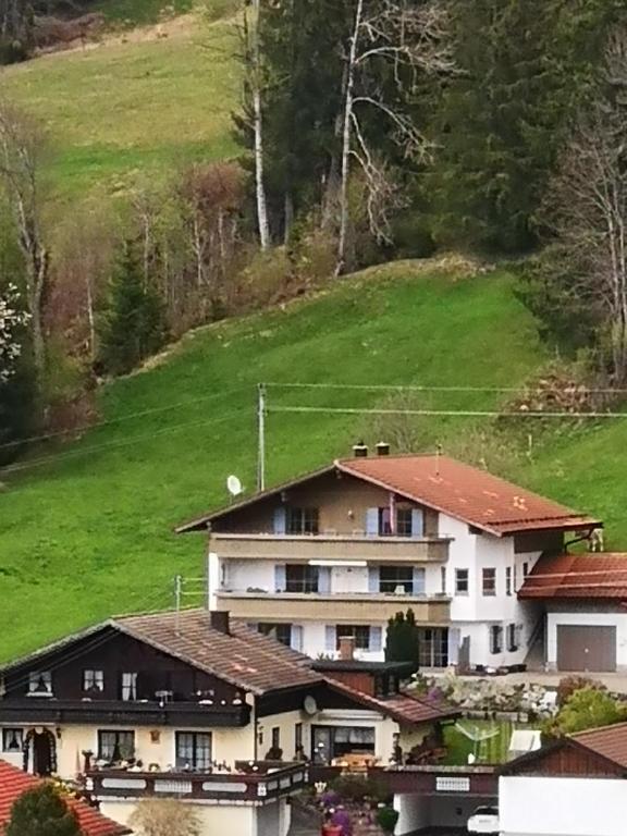 a large house with a green hill in the background at Jungholz Erlebnis in Jungholz