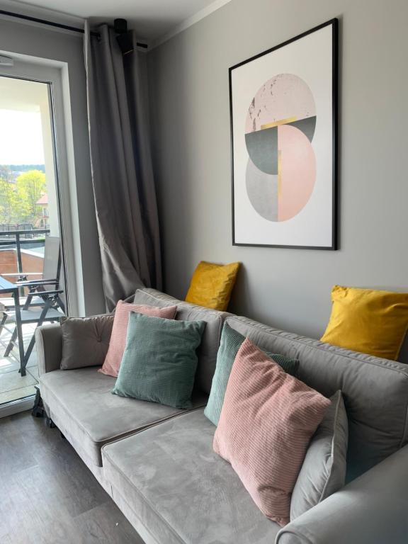 米茲多洛傑的住宿－Sand Apartament Bel Mare Aqua，客厅配有带色彩缤纷枕头的沙发