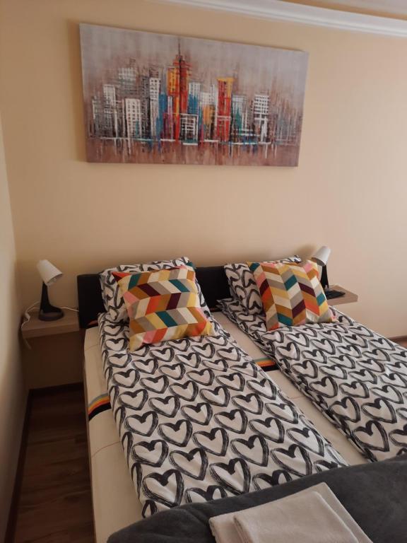 een woonkamer met 2 bedden en een schilderij aan de muur bij Sunset in Palić
