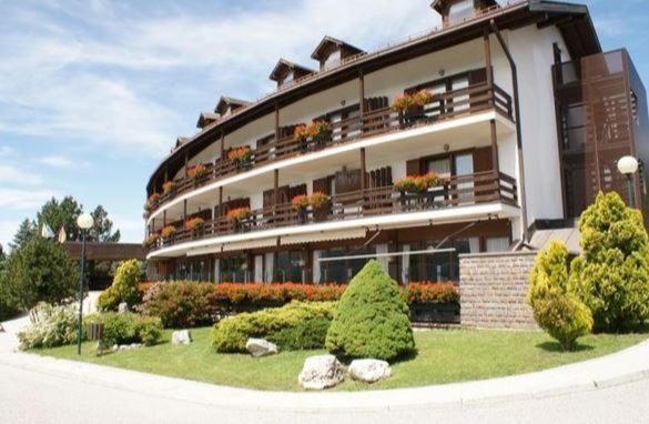 a large building with flowers and plants in front of it at Appartamento "Sergio" presso Residence Veronza 7 posti letto in Cavalese