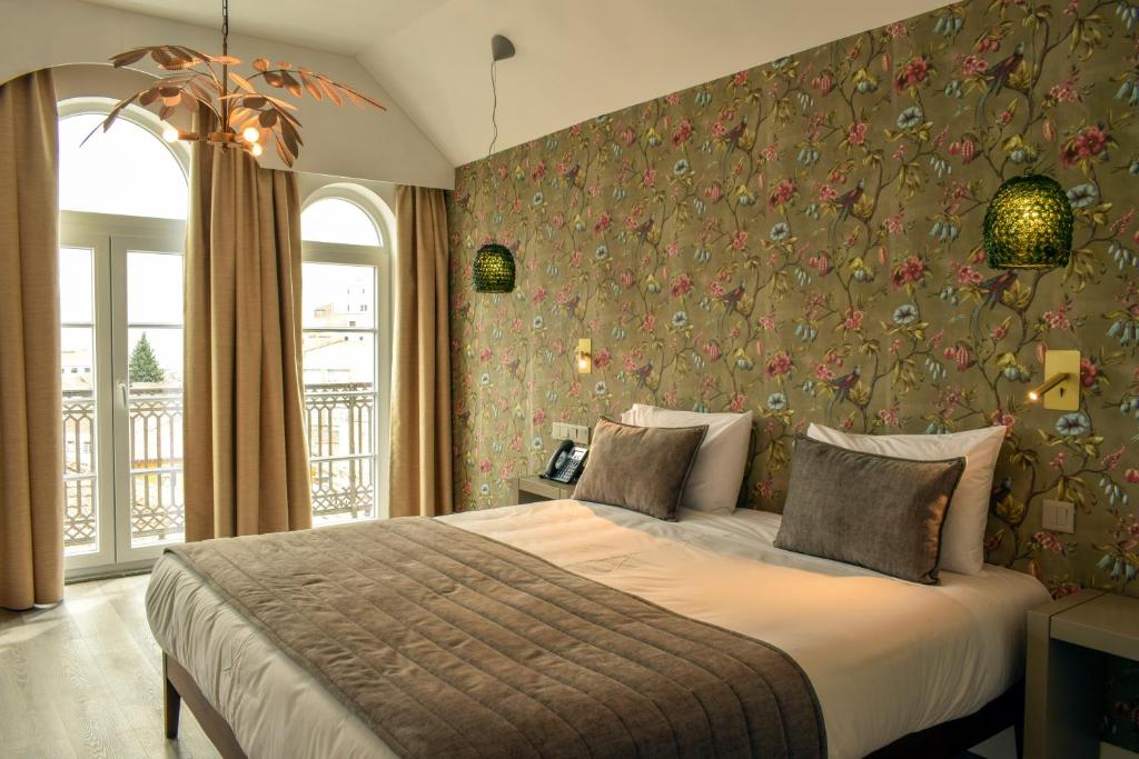 1 dormitorio con 1 cama grande y papel pintado con motivos florales en Arte Nova Guesthouse, en Covilhã