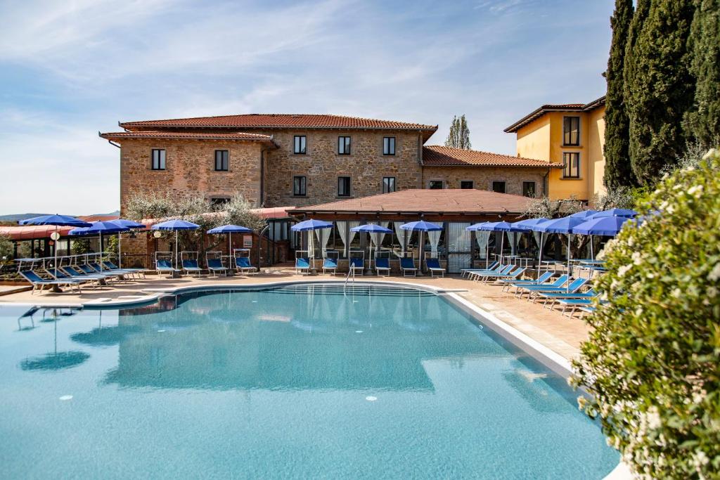 a pool with chairs and umbrellas in front of a building at Hotel Villa Paradiso in Passignano sul Trasimeno