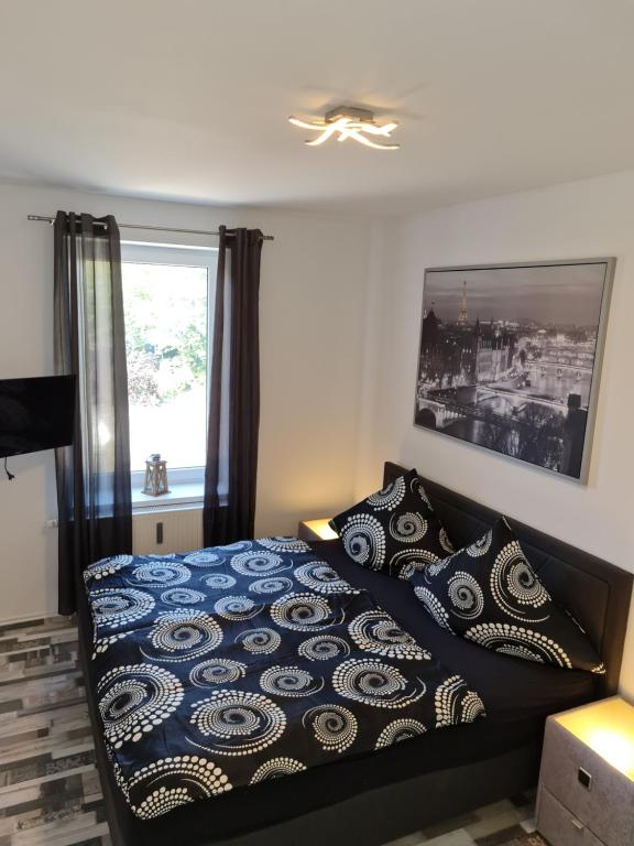 ein Schlafzimmer mit einem Bett mit blauer Decke und einem Fenster in der Unterkunft City Apartment in Osnabrück