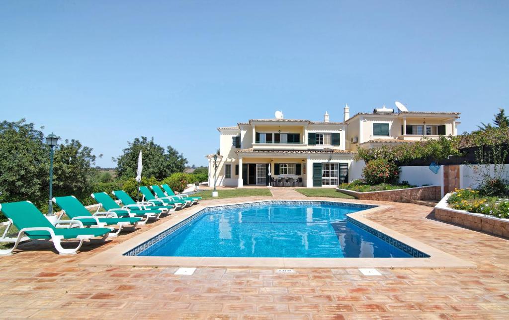 a swimming pool with chairs and a house at Casa dos Avós in Albufeira