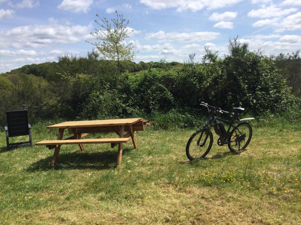 un vélo garé à côté d'une table de pique-nique et d'un banc dans l'établissement EcoCamping d Hacadour, à Mellionnec