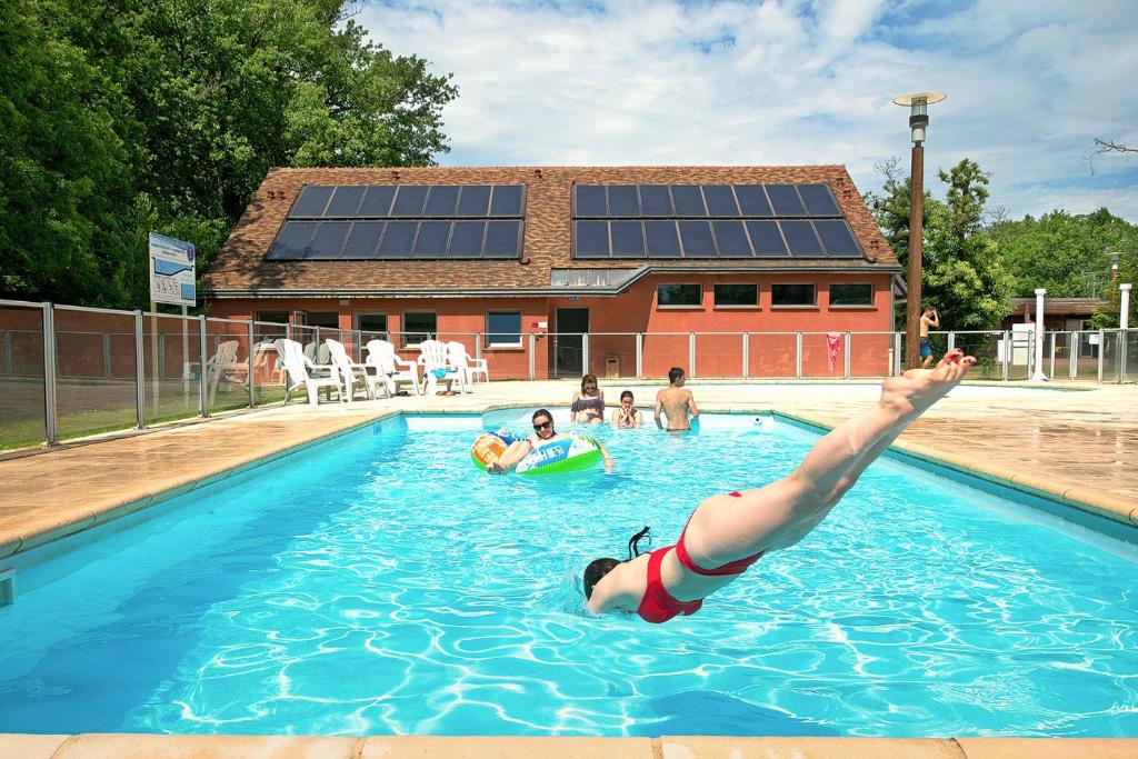 une personne dans une piscine avec ses pieds dans l'eau dans l'établissement Camping Onlycamp Le Pont Romain, à Yvré-lʼÉvêque