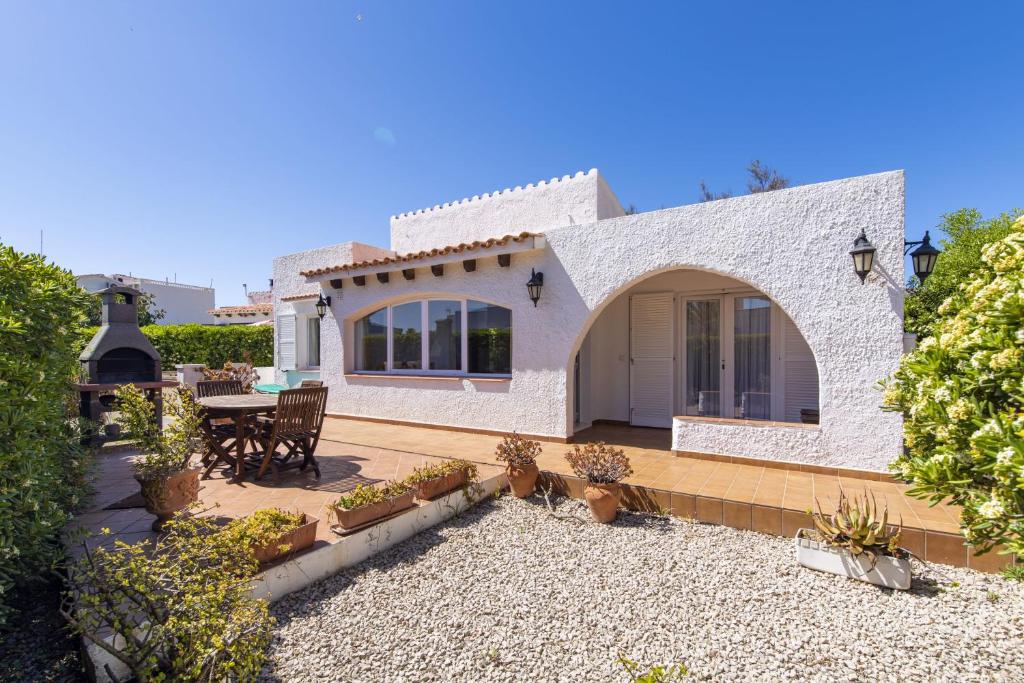 Cette maison en briques blanches dispose d'une terrasse et d'une table. dans l'établissement Villa Rosa, à S'Algar