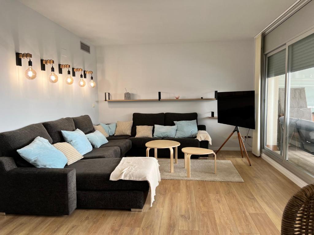 ein Wohnzimmer mit einem schwarzen Sofa und einem TV in der Unterkunft Apartament Montsià in Sant Carles de la Ràpita