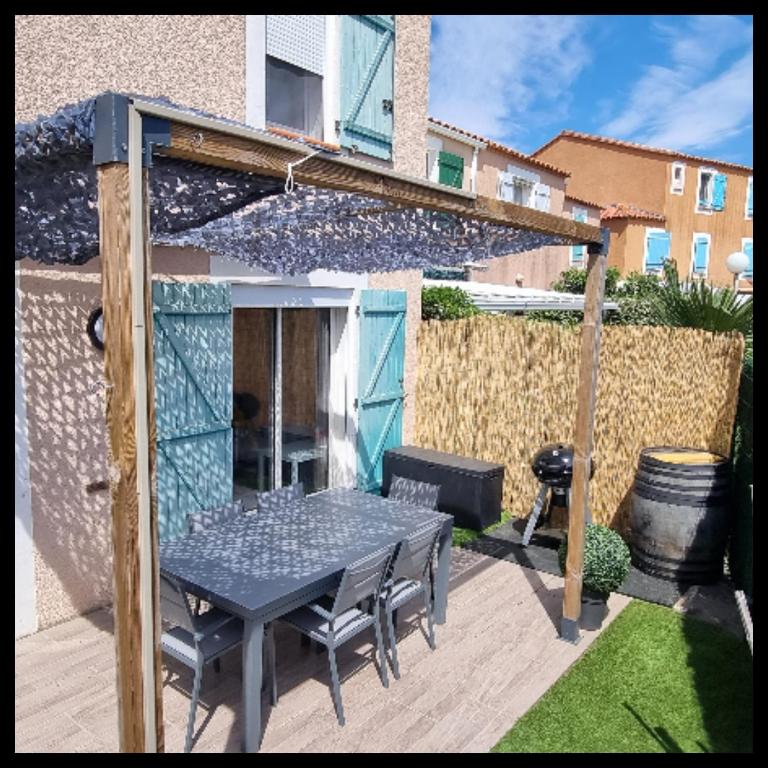 eine Terrasse mit einem Tisch, Stühlen und einem Zaun in der Unterkunft Maison de vacances Torreilles plage 6 personnes in Torreilles