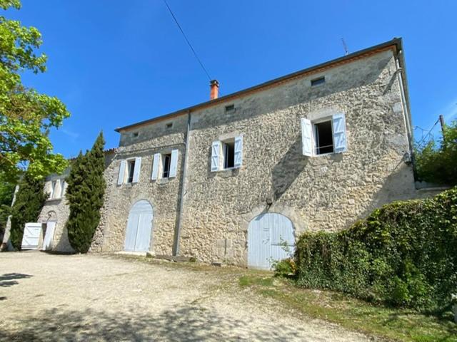 ein großes Steingebäude mit weißen Türen und Fenstern in der Unterkunft Gite de groupe "L'Unisson" Domaine La Rose des Vents in Castelnau-sur-lʼAuvignon