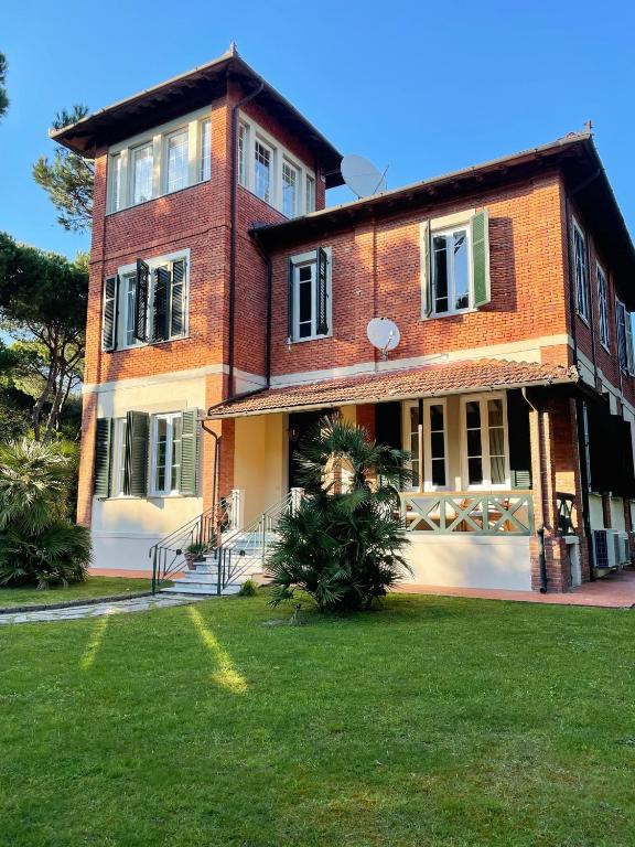 a large brick building with a green lawn in front of it at Villa Liberty al mare in Marina di Massa
