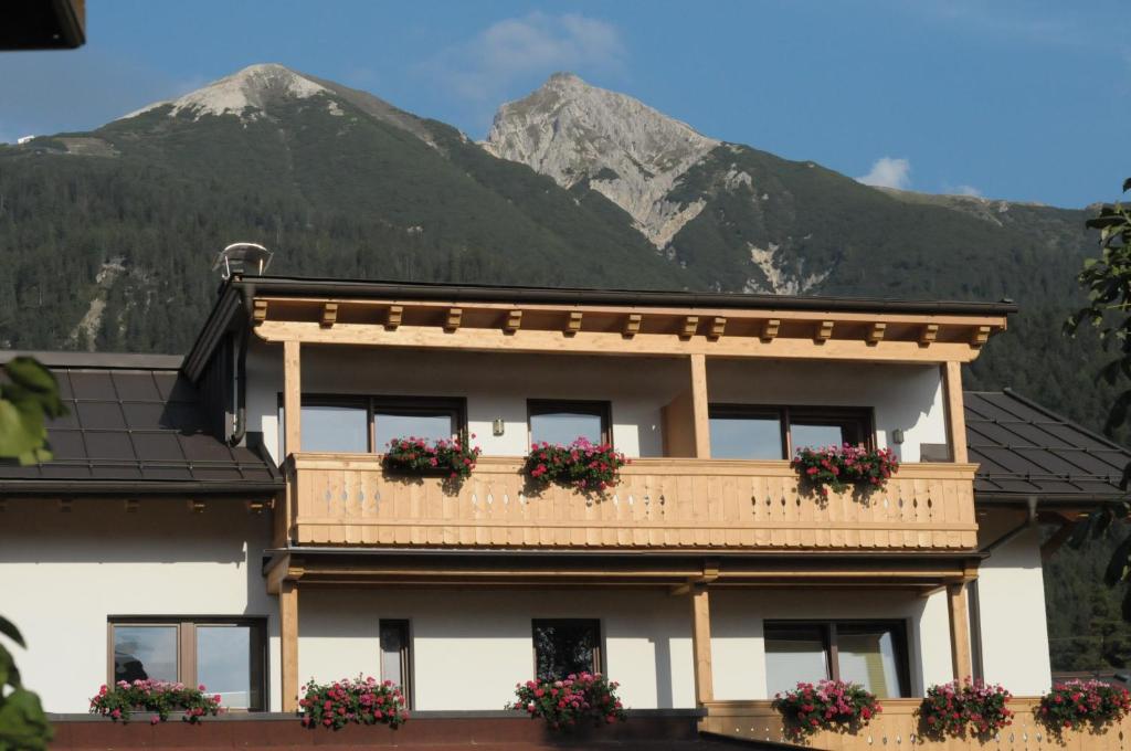 a building with flowers on the balcony with mountains in the background at Haus Lagger in Seefeld in Tirol