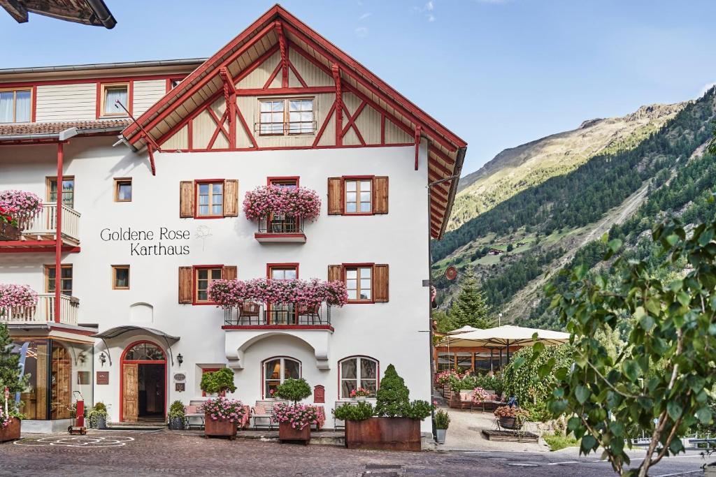 ein Gebäude in den Bergen mit Blumen in den Fenstern in der Unterkunft Goldene Rose Karthaus a member of Small Luxury Hotels of the World in Schnals