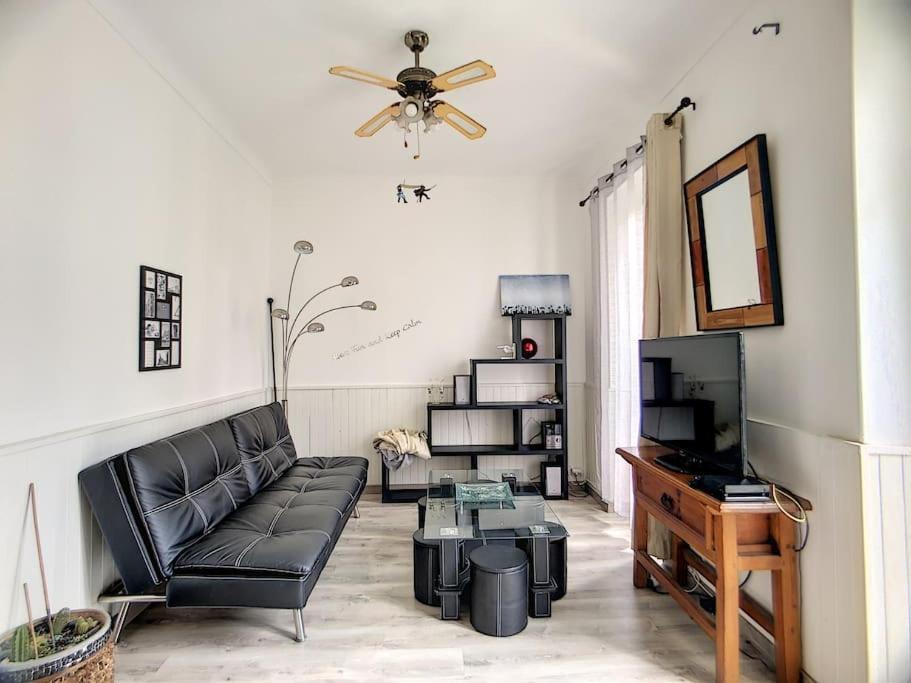 un salon avec un canapé noir et une télévision dans l'établissement Joli 3 pièces, 7 pers, très lumineux, Nice centre, à Nice