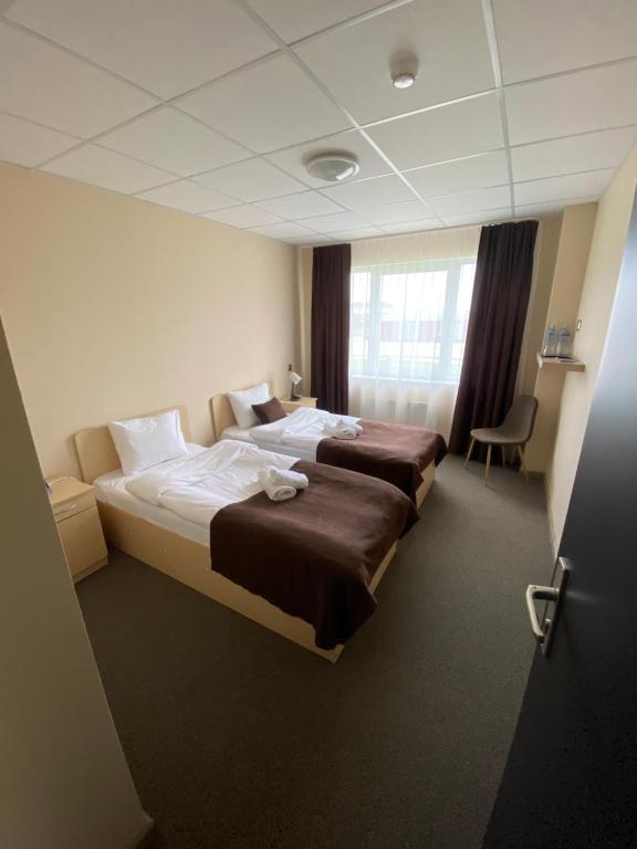 una camera d'albergo con due letti e una finestra di VILARHOTEL ad Aizkraukle