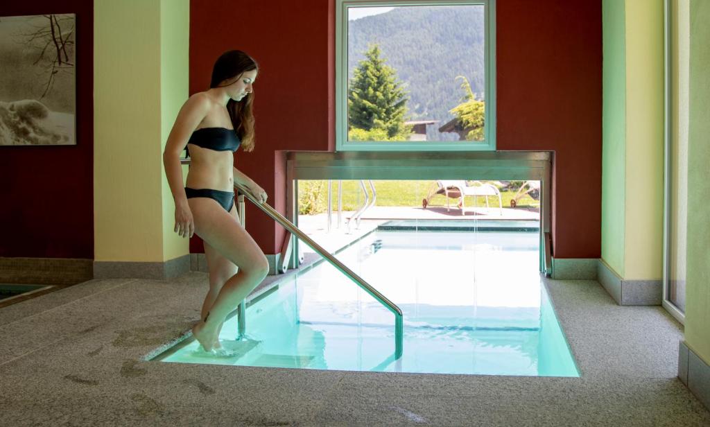 una mujer en bikini parada en una piscina en Nature Wellness Hotel Renato en Vigo di Fassa