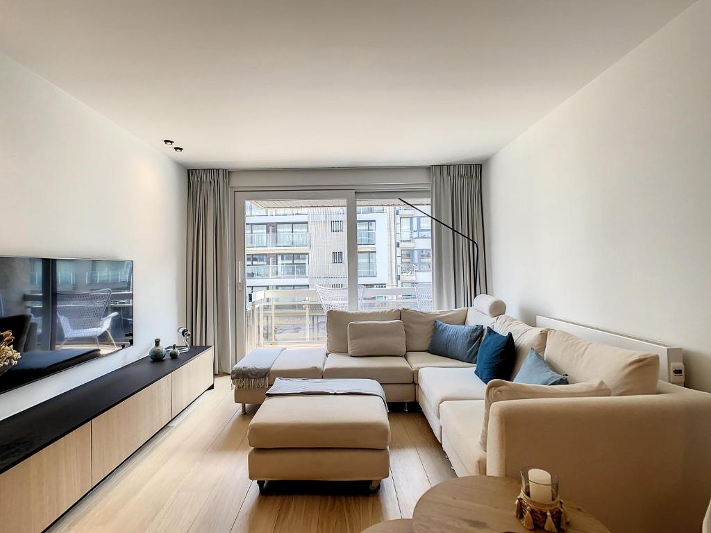 a living room with a couch and a tv at Vakantieappartement 'De Strandjutter' te Oostduinkerke in Oostduinkerke