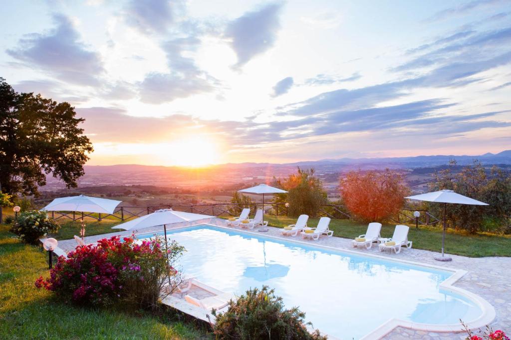 a pool with chairs and the sunset in the background at San Giovanni al Monte in Collazzone