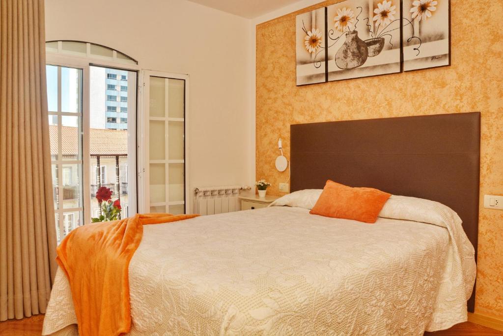 Un dormitorio con una cama grande y una ventana en Hostal la Colegiata, en Vigo