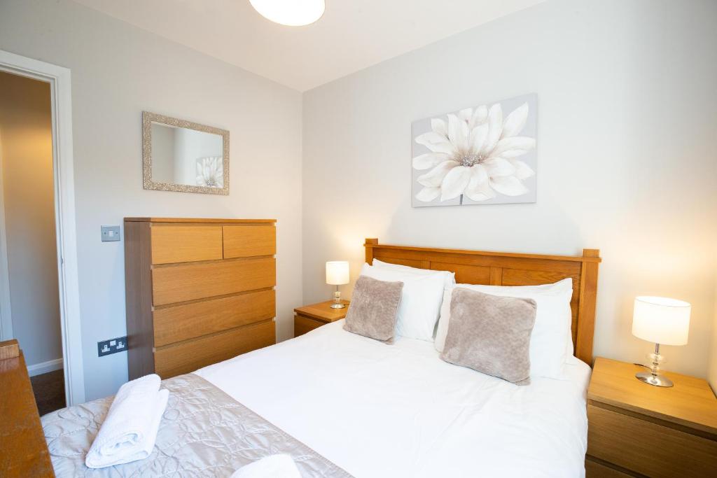 Velvet 2-bedroom apartment, Brewery Road, Hoddesdon في هوديسدون: غرفة نوم بسرير ابيض ومصباحين