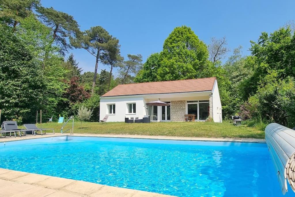 una casa con piscina frente a una casa en Jolie maison en pleine nature, en Villiers-sous-Grez