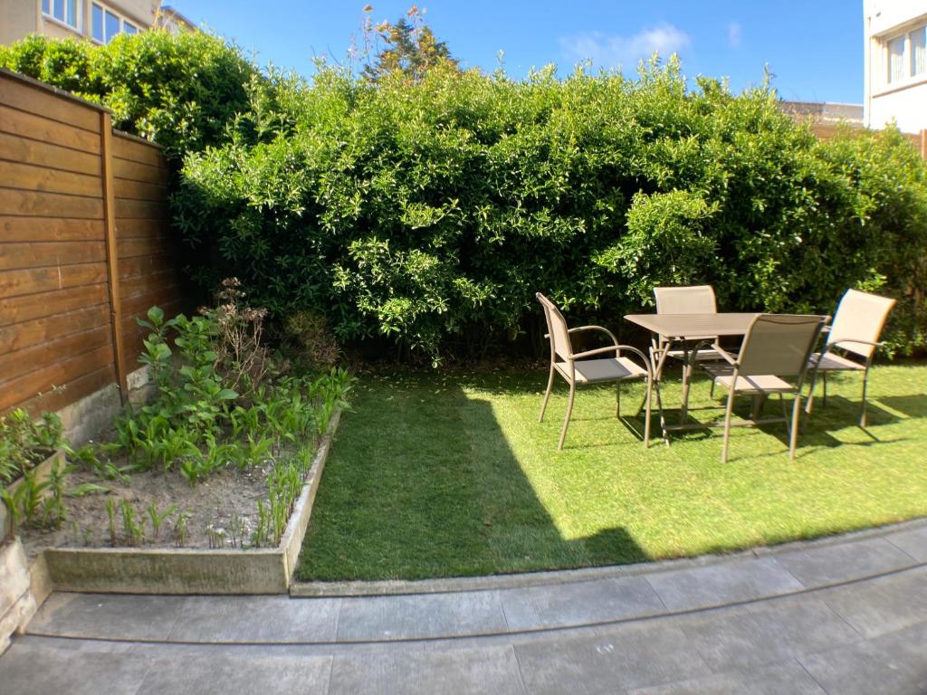 un jardin avec une table et des chaises sur la pelouse dans l'établissement Résidence About Malo RDC avec jardin lumineux à 2 pas de la plage, à Dunkerque