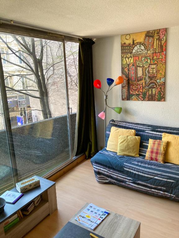 un salon avec un canapé et une grande fenêtre dans l'établissement Le Studio Victoria II -Mon Desert Village -27m2, à Nancy