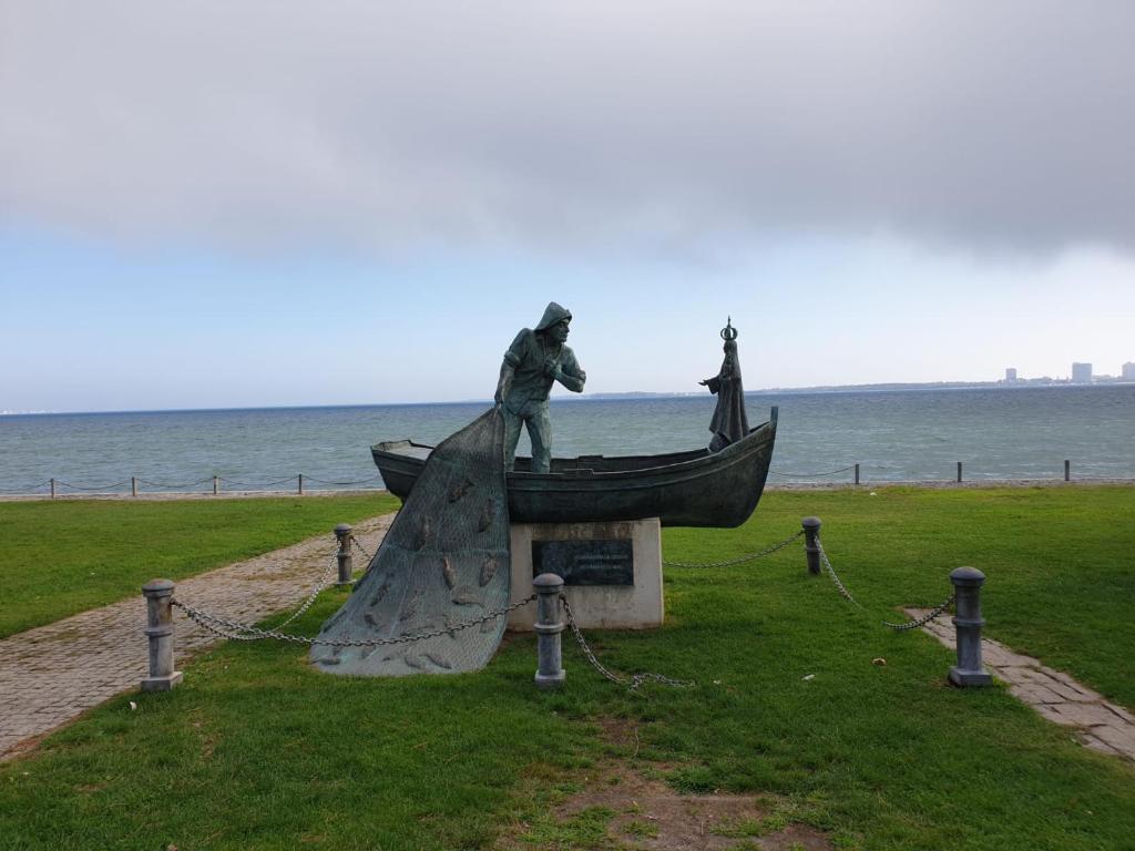 eine Statue von zwei Personen auf einem Boot auf einem Feld in der Unterkunft Setúbal Health Beach in Setúbal