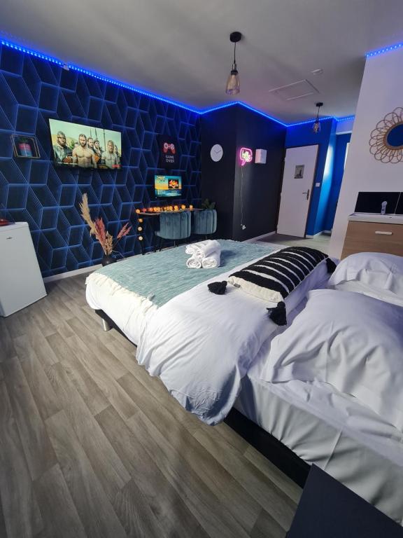 een slaapkamer met een groot bed en een blauwe muur bij NG SuiteHome - Lille I Roubaix Centre I 121 - Gamer - Arcade de jeux - Netflix - Wifi in Roubaix