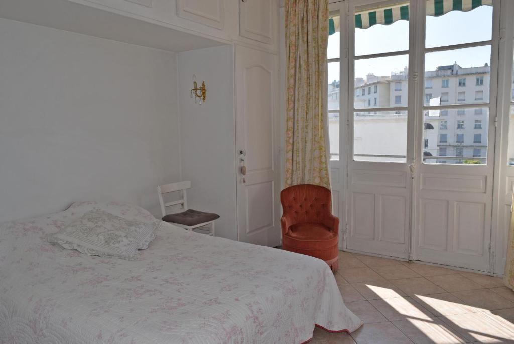 une chambre avec un lit, une chaise et une fenêtre dans l'établissement Palais Alexandre III, à Cannes