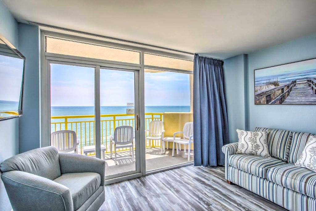 a living room with a couch and a balcony with the ocean at Beachside Retreat North Myrtle Beach Condo! in Myrtle Beach