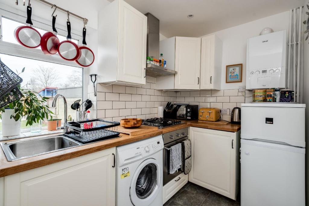 een keuken met witte kasten, een wastafel en een vaatwasser bij Tasteful 3-Bedroom House with private parking - Florence Park in Oxford