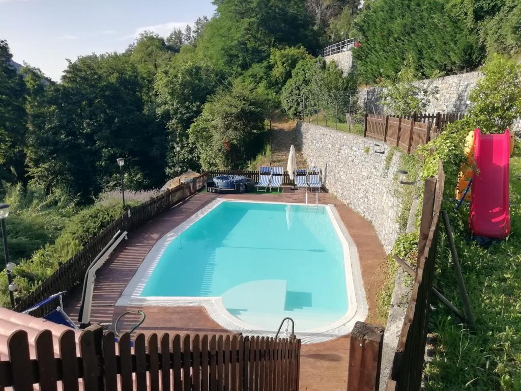 a swimming pool with a wooden deck and a blue swimming pool at La Sorgente Appartamento con piscina privata in Calice Ligure