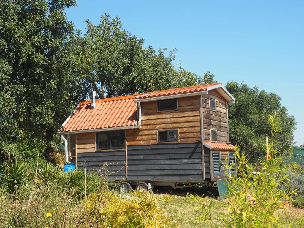 uma casa de madeira com um telhado laranja num campo em Tiny house eco resort em Estevais