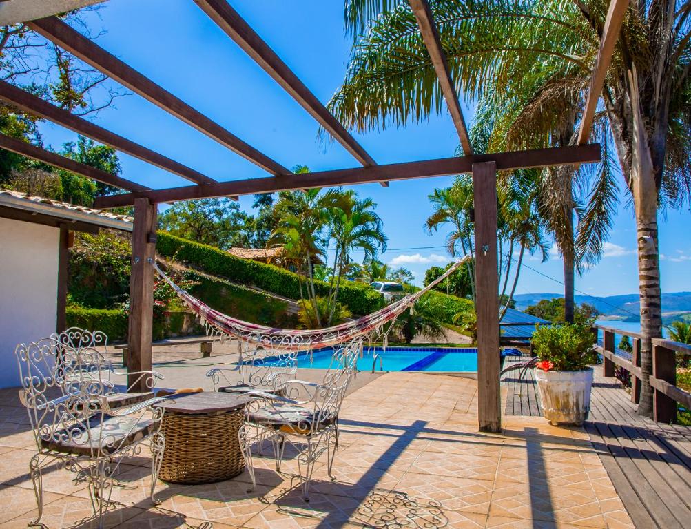 eine Terrasse mit Stühlen und einer Hängematte neben einem Pool in der Unterkunft Vista do Lago in Capitólio