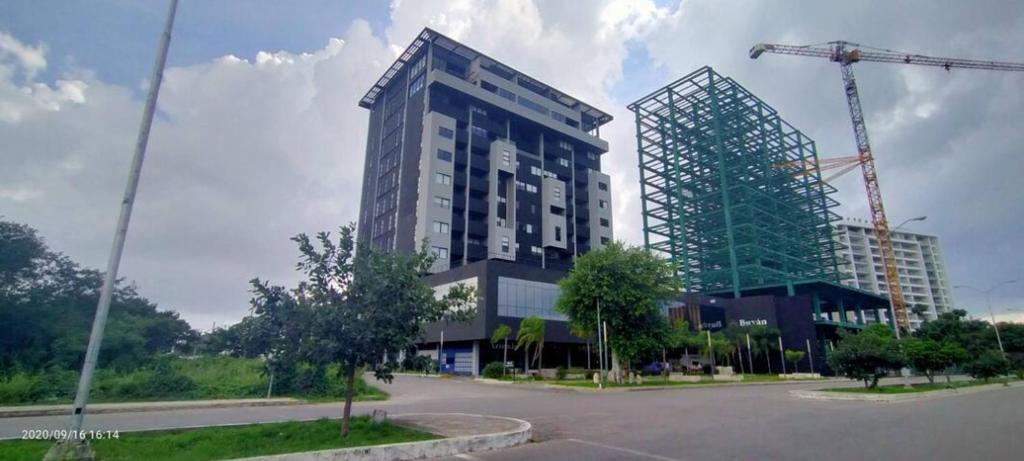 un edificio alto con una grúa delante de él en Buyan Departamentos, en Mérida