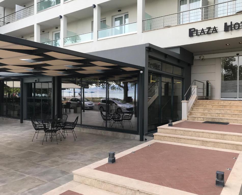 Plaza Hotel في نافباكتوس: مبنى فيه كراسي وطاولات خارجه