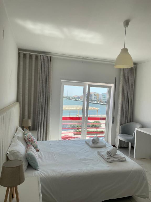 een slaapkamer met een bed en uitzicht op de oceaan bij Dom Quixote apartamentos turísticos in Praia de Mira