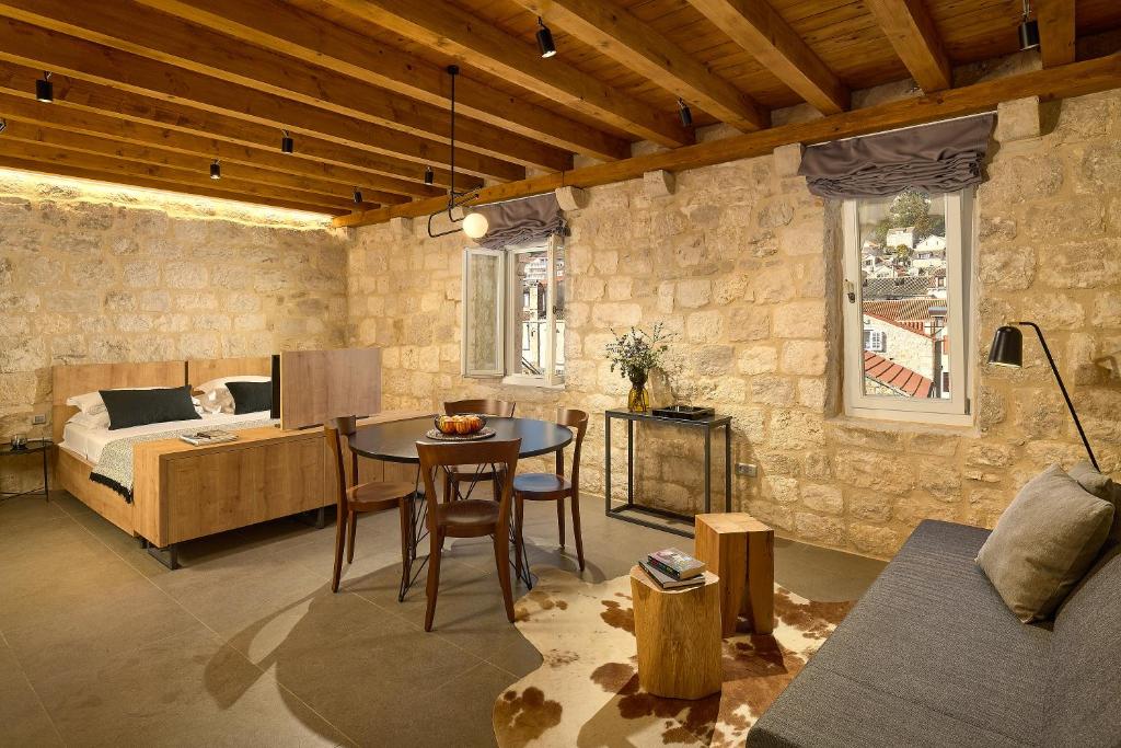 a room with a bed and a table and a bedroom at History Hvar Design Heritage Suites in Hvar