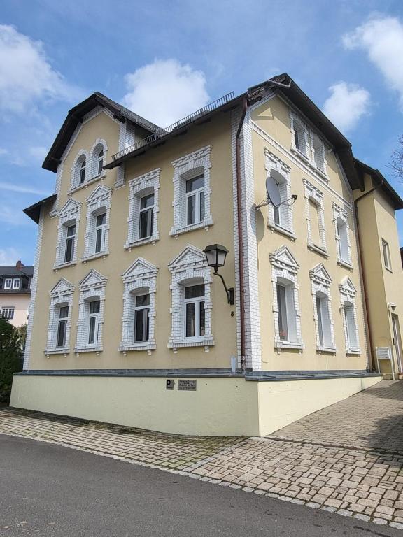 a yellow building with white windows on a street at Ferienwohnung Sonnenhaus in Wonsees