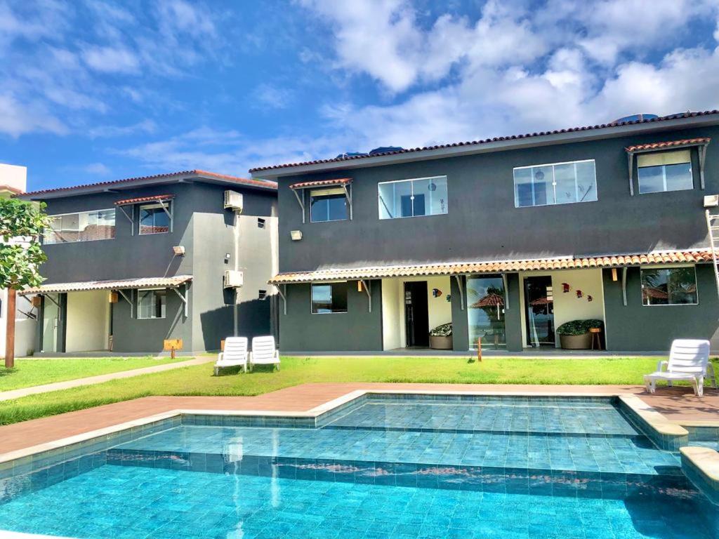 a house with a swimming pool in front of a house at Condomínio Praias de Maragogi & Casas Deluxe in Maragogi