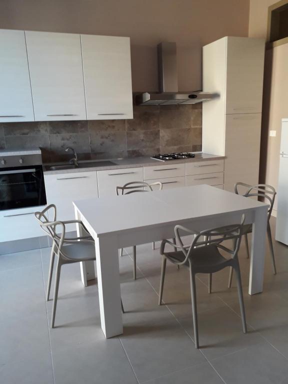 a white kitchen with a white table and chairs at CASA DI AGNESE in Altavilla Milicia