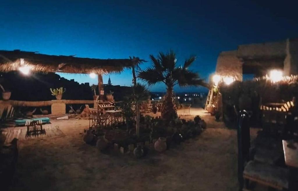 a night view of a patio with a palm tree at NaInshal Siwa in Siwa