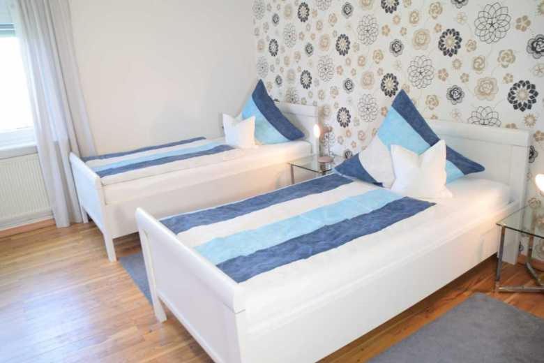 a bedroom with two beds with blue and white pillows at DEB 035 Ferienwohnung im Westerwald in Freirachdorf