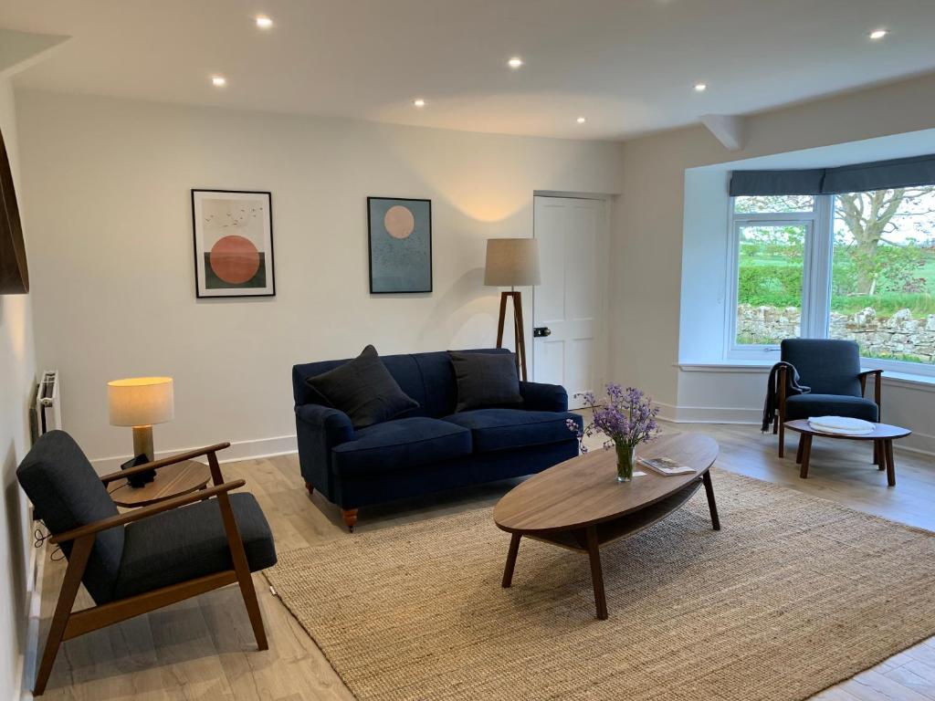 a living room with a blue couch and a table at Border View Cottage in Duddo