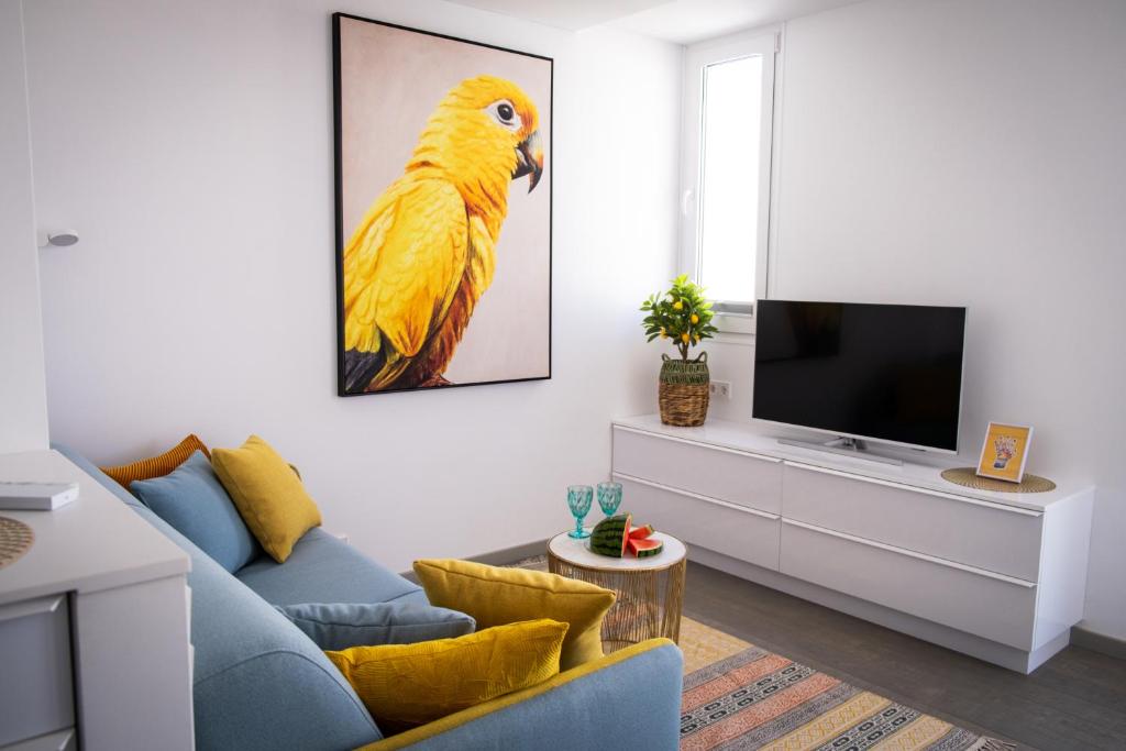 a living room with a yellow parrot painting on the wall at AMBER APARTMENTS - SUNNY STUDIO in Morro del Jable