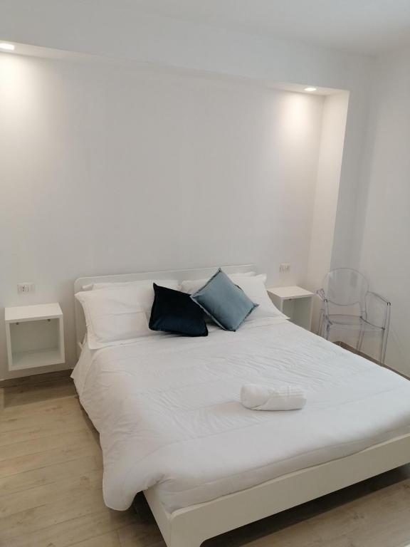 a white bed with two blue pillows on it at A casa di Maghi in Olbia