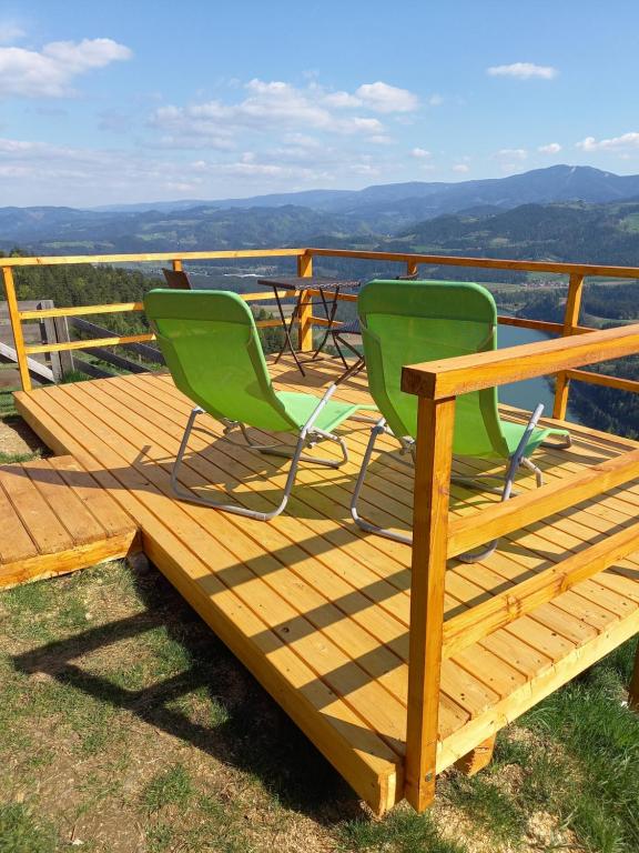 2 Stühle und ein Tisch auf einer Terrasse mit Aussicht in der Unterkunft Glamping hišice Orlič in Muta